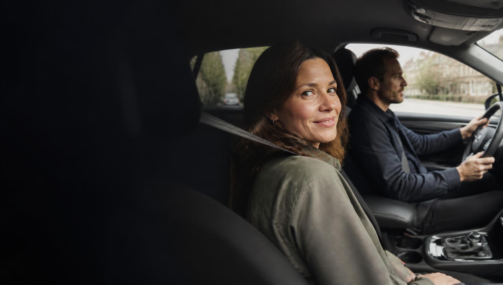 A woman smiling from the passenger seat while her partner drives